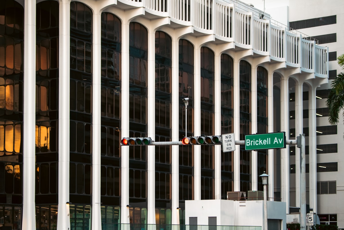 Colonnes blanches en arc d’un immeuble de bureaux moderne derrière le panneau vert Brickell Av et des feux de circulation