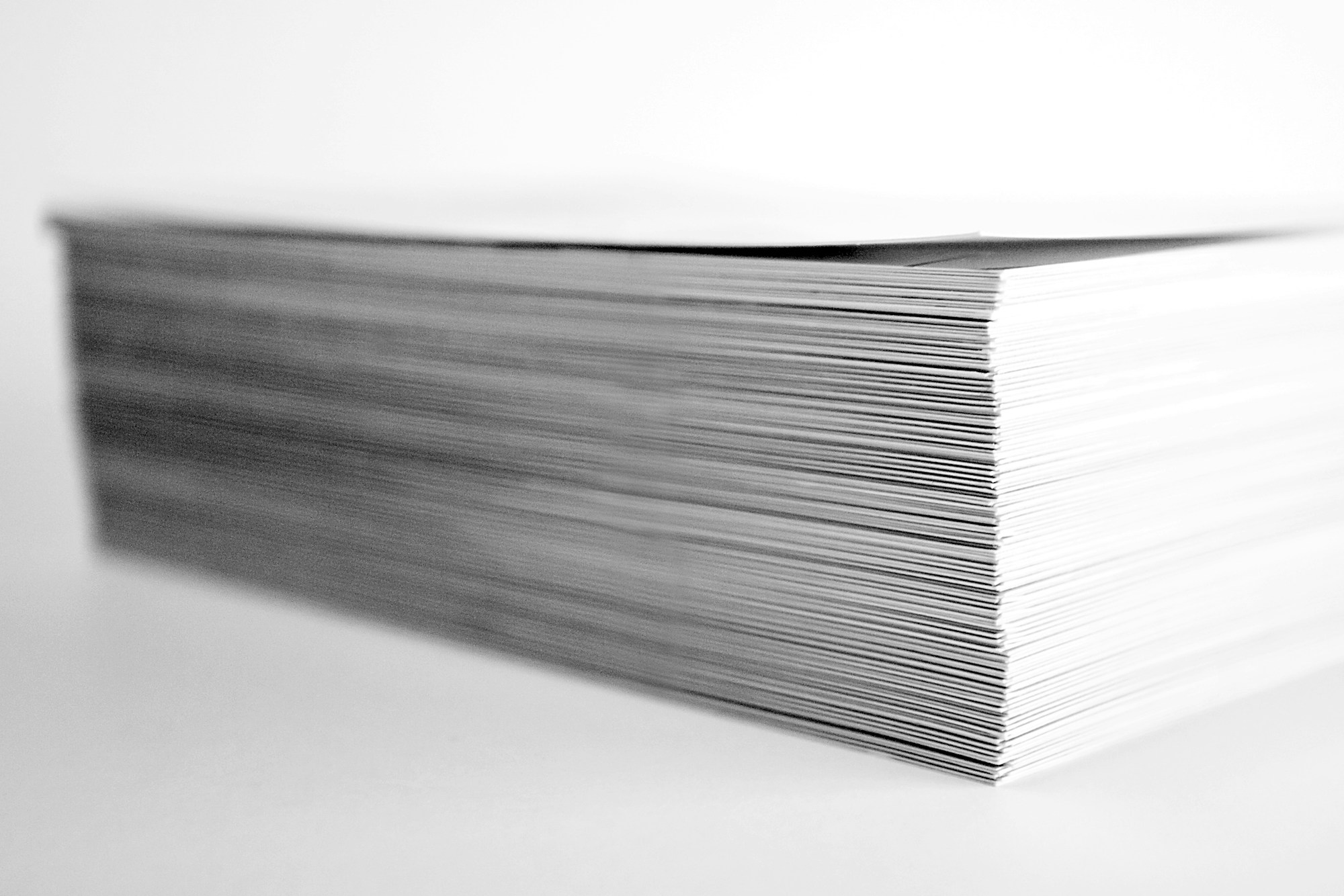 Close-up side view of a stack of paper sheets, in black and white