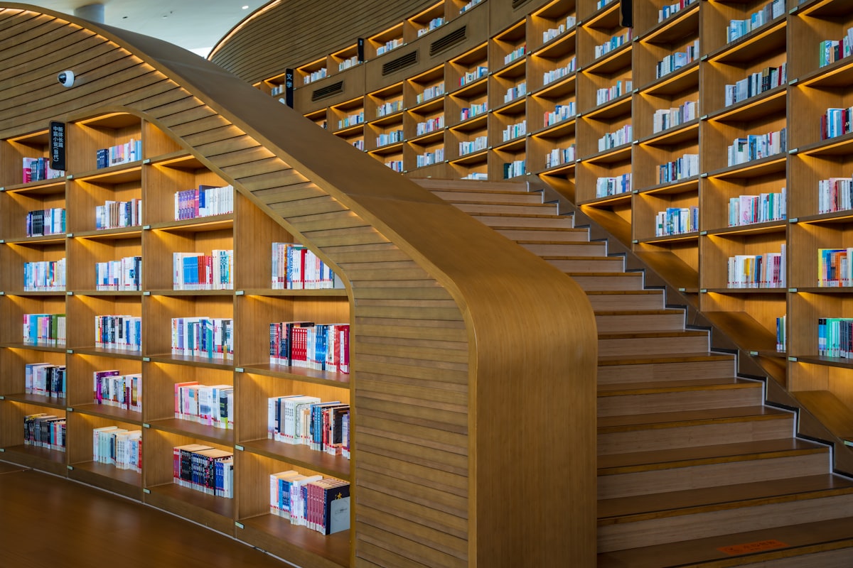 Bibliothèque en bois aux lignes courbes, rayonnages remplis de livres le long d’un escalier