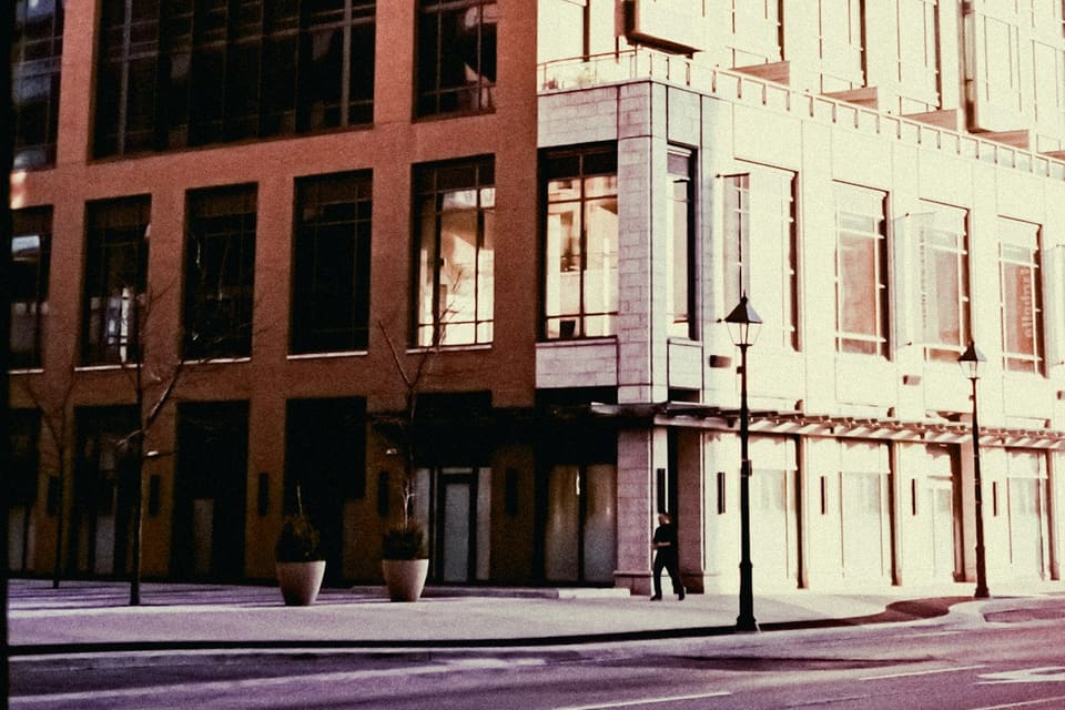 Corner of a modern office building with a glass facade catching warm light above a quiet street