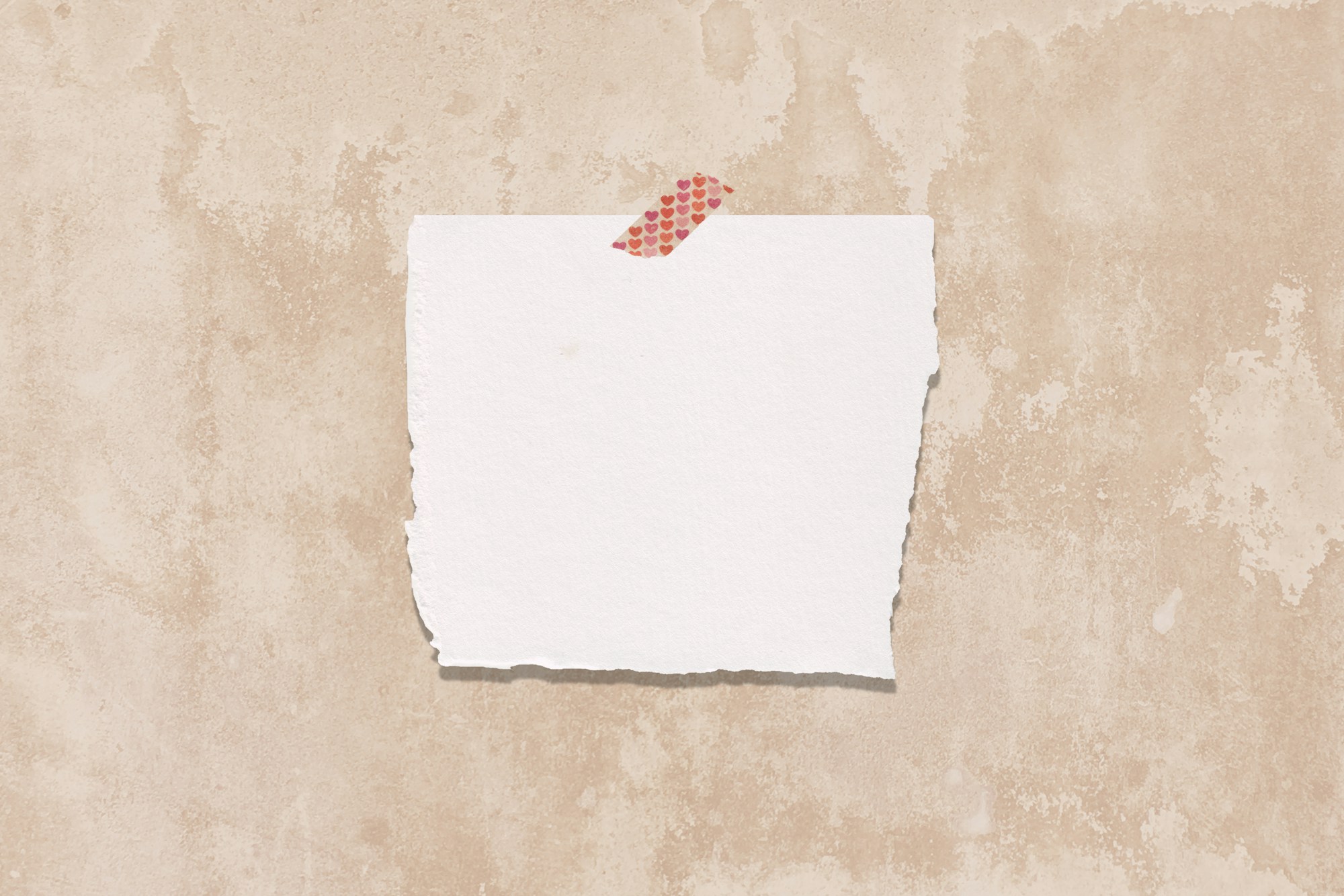 Torn sheet of white paper held by a strip of heart-patterned tape on a weathered beige plaster wall
