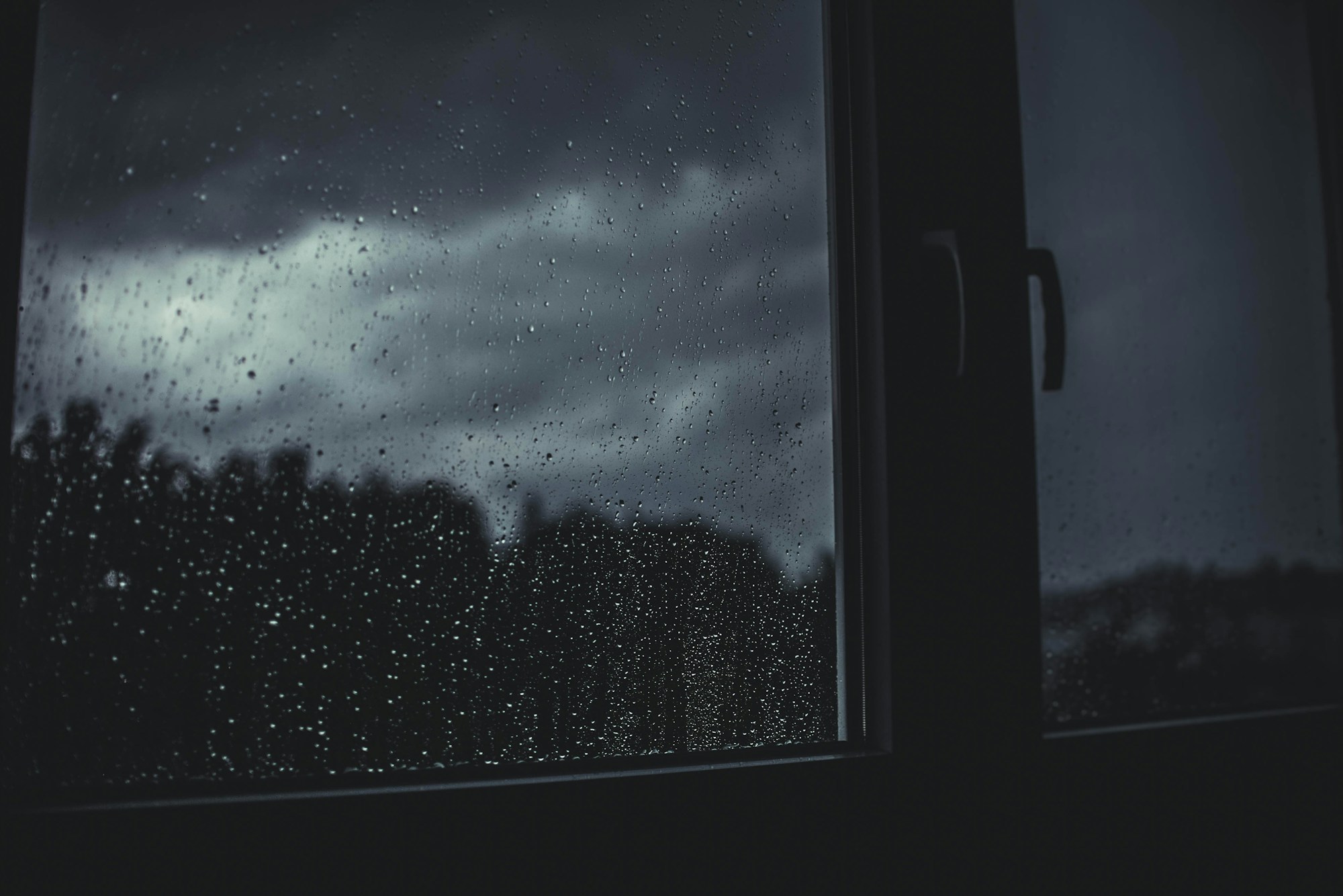 Silhouette einer einzelnen Person an einem Fenster im Regen