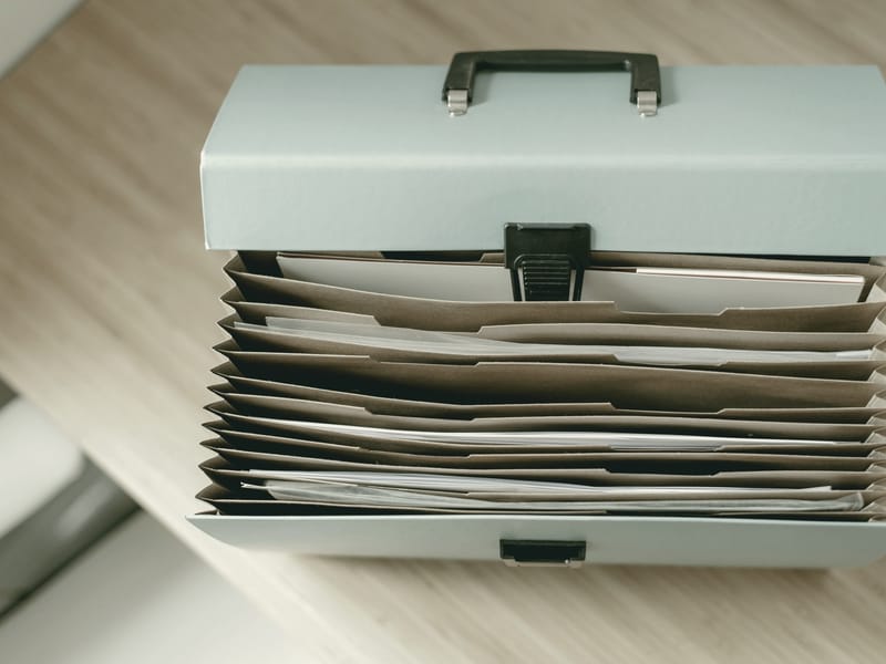 An open file box on a desk, its folders filled.